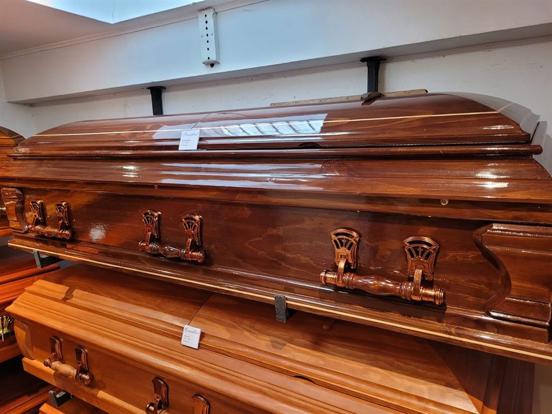 Ataúd de madera oscura con herrajes de bronce